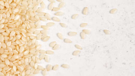 White sesame - Sesamum indicum - seeds on white stone like board, view from aboveの写真素材
