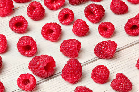 Raspberries spilled on white boards desk.