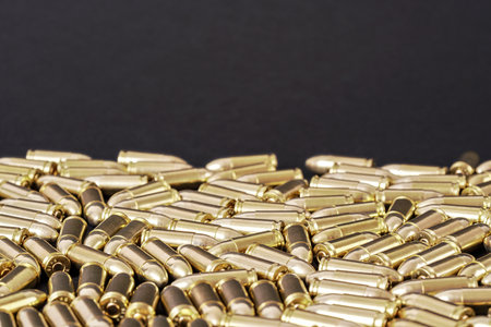 Many brass gun bullets on black table closeup view, space for text upper side