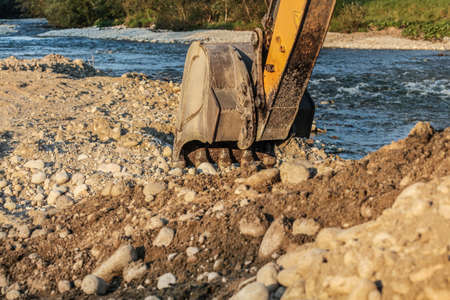 Excavator (digging machine) bucket digging ground by the river.の写真素材