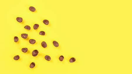 Tabletop view chocolate corn flakes scattered on yellow board, space for text on right side.の写真素材
