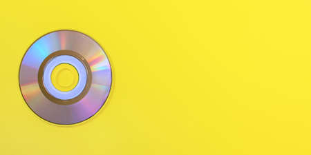 Top down view, small CD shiny / rainbow side, on yellow board, space for text on right side.の写真素材