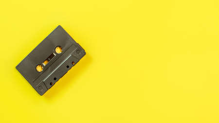 Top down view, old audio tape in cassette on yellow board, space for text on right side.の写真素材