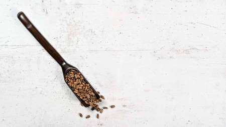 Blessed milk thistle seeds - Silybum marianum - in small wooden spoon on white stone like board, view from above, space for text right sideの写真素材