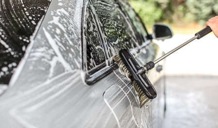 Side of silver car washed in self serve carwash. Detail on brush leaving strokes in shampoo foam.の写真素材