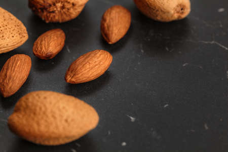 Closeup of almonds, both peeled and whole, on dark board. Space for text on right side.の写真素材