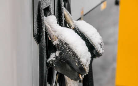 Snow covered fuel nozzles on gas station.