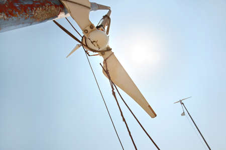 Looking up small broken wind turbine, strong midday sun shining on the sky.の写真素材