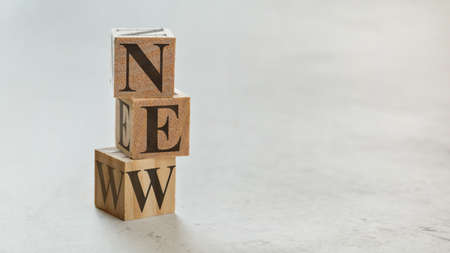 Pile with three wooden cubes - letters NEW on them, space for more text / images on right side.の写真素材