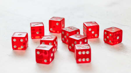 Ten red translucent craps dices on white board showing different numbers.の写真素材