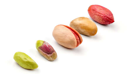 Pistachios in different stages from peeled green fruit, through roasted and salted to raw in purple skin, isolated on white background.の写真素材