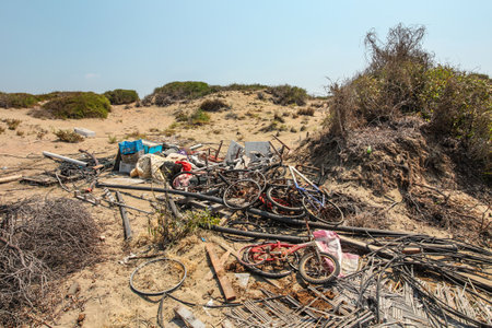 Pile of old rusty discarded bicycles laying on sand in strong sun. All brands / logos removed.の写真素材