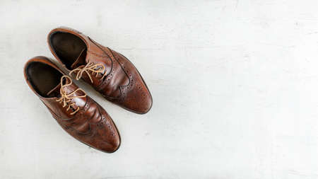 Top down view, worn classic dark brown brogue shoes on white board. Wide banner with space for text right.の写真素材