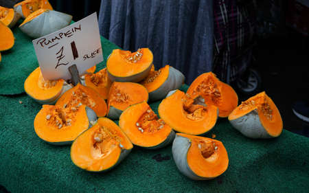 Green / orange pumpkins sliced to quarters on display at food market in Londonの写真素材