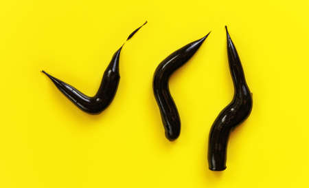Three thick black cream smears charcoal toothpaste on yellow background, view from aboveの写真素材