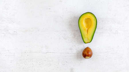 Exclamation mark made of avocado half and seed, on white board, photo from above. Wide banner with space for text on left side.の写真素材