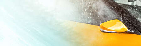 Side mirror and window of orange vehicle washed in self serve car wash, left part filled with abstract shampoo streaks on glass - wide carwash banner, copy space for text.の写真素材