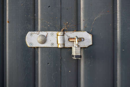 Old padlock, parts covered with rust, on gray wood fence.の写真素材