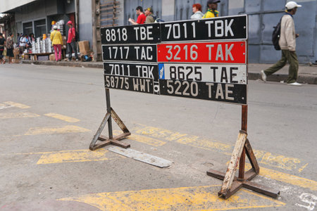 Antananarivo, Madagascar - April 24, 2019: Car license plates displayed near road (at auto garage shop), blurred people walking in backgroundのeditorial素材