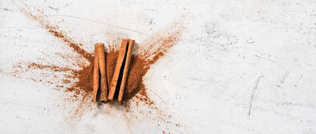 Closeup detail - cinnamon bark and milled powder on white stone board, view from above, space for...