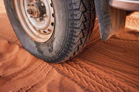 4wd vehicle tyre, dirty from dust - track print visible in red sand, closeup detail