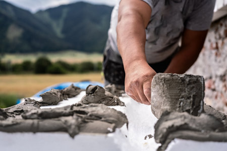 Installing white polystyrene heat insulation, detail on worker hand putting gray bonding cement glue on white boardsの写真素材