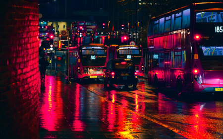 London, United Kingdom - February 01, 2019: Buses and taxis stuck in heavy traffic on a rainy evening near Lewisham station, bright red lights reflected in wet road and pavementのeditorial素材