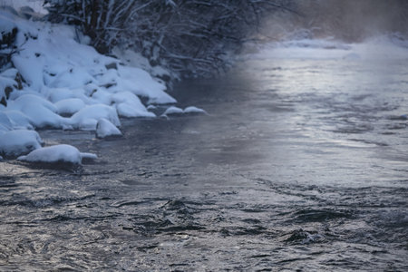 Cold winter river, steam visible above water, dark trees on both sides