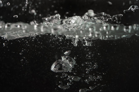 Water splashing as it's poured into aquarium tank, black backgroundの写真素材