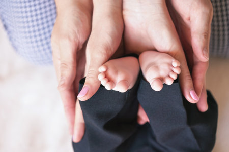 Parents hands holding little baby boy feet, view from aboveの写真素材