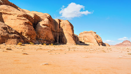 Rocky massifs on red sand desert, bright blue sky in background - typical scenery in Wadi Rum, Jordanの写真素材