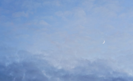 Evening sky with some barely visible clouds, moon crescent in right side - blue hour backgroundの写真素材