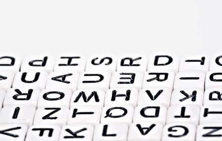 Small white cube beads with various letters arranged next to each other, closeup detailの写真素材