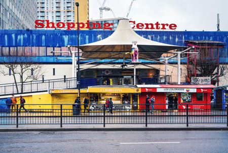 London, United Kingdom - February 04, 2019: Elephant and Castle shopping centre, with small shops in front. People walking on pavement next to road, cold overcast day. Building was closed late 2020のeditorial素材