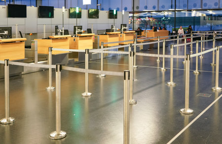 Schwechat, Austria - April 22, 2019: Empty waiting area divided with tape boundaries at check in desks of Vienna airport, blurred at people backgroundのeditorial素材