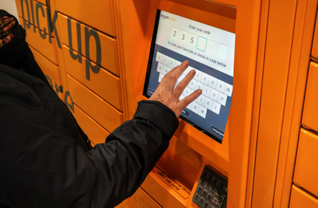 London, United Kingdom - February 04, 2019: Elderly woman entering code at orange Amazon (online...