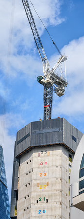 Tall modern skyscraper construction, concrete walls with numbers marking floors to be built, large...