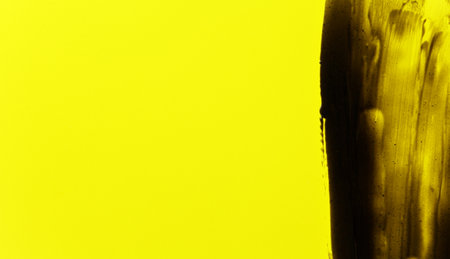 Abstract black smears (charcoal toothpaste) on yellow background, space for text left sideの写真素材