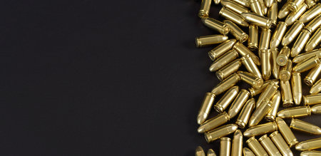 Many brass gun bullets on black table closeup view from above, space for text left sideの写真素材