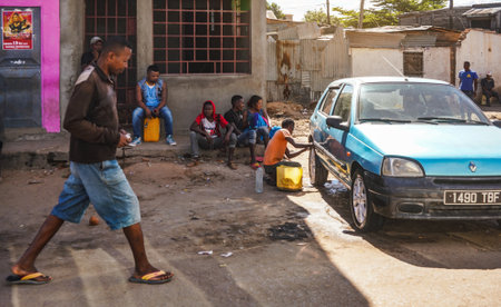 Ilakaka, Madagascar - May 05, 2019: Group of unknown Malagasy people sitting on stone porch, man...