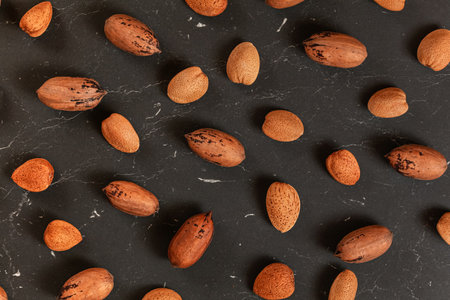 Mixed whole pecan nuts and almonds on black marble board, flat lay photoの写真素材