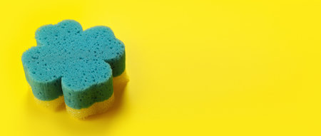 Blue bathroom clover shaped sponge on yellow board, space for text right side
