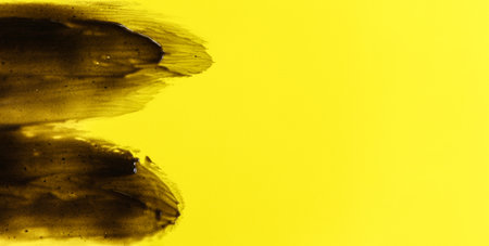 Abstract black smears (charcoal toothpaste) on yellow background, space for text right sideの写真素材