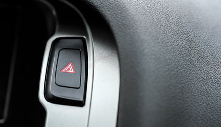 Red warning light triangle button in modern car interior panel, closeup detailの写真素材