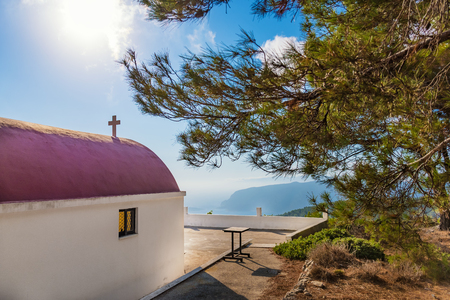 View of Greek orthodox church with cyclamen roof next to forest (Rhodes, Greece)の写真素材