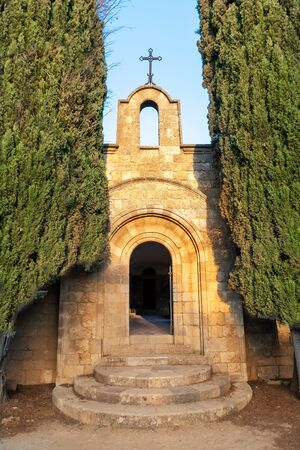 Side entrance in between thujas trees to Monastery of Filerimos on Acropolis of Ialyssos (Rhodes, Greece)の写真素材