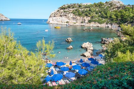 Small beach with tourists, umbrellas and sun chairs in Anthony Quinn bay (Rhodes, Greece)の写真素材