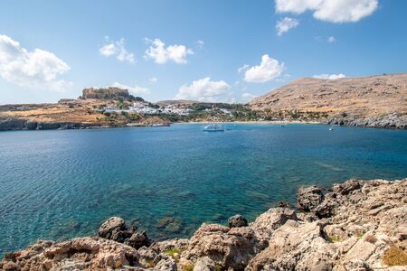 Lindos bay with boats, white houses of village of Lindos and Acropolis in background (Rhodes,...