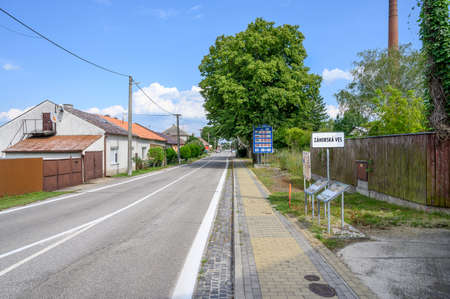 Entrance road to village Zahorska Ves with big blue board with speed limits in Slovakia (SLOVAKIA)の写真素材
