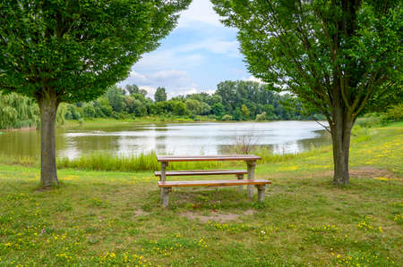 Bench under trees by lake in Angern an der March (AUSTRIA)の写真素材